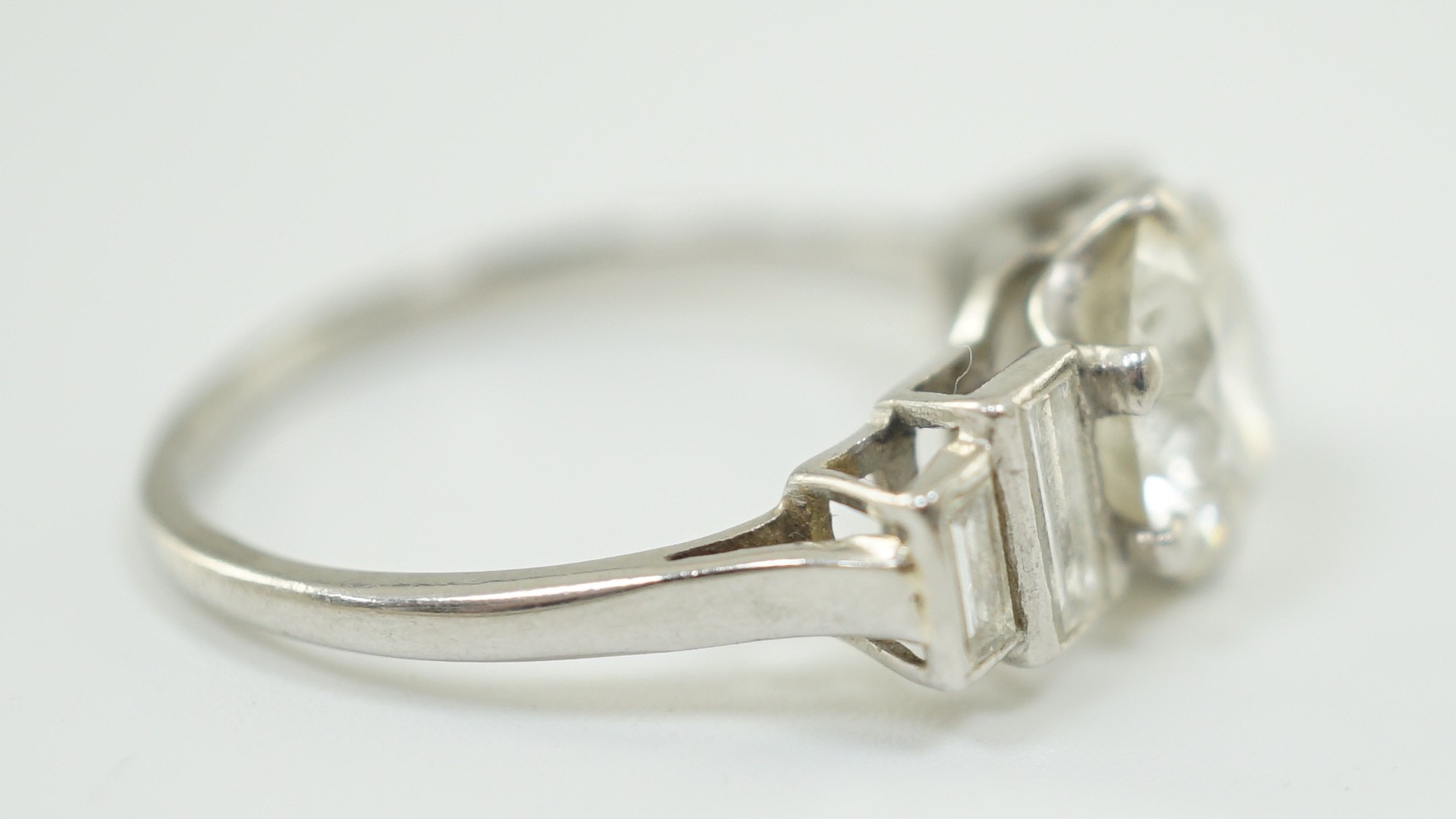 A platinum and single stone diamond ring, with graduated baguette cut diamond set shoulders